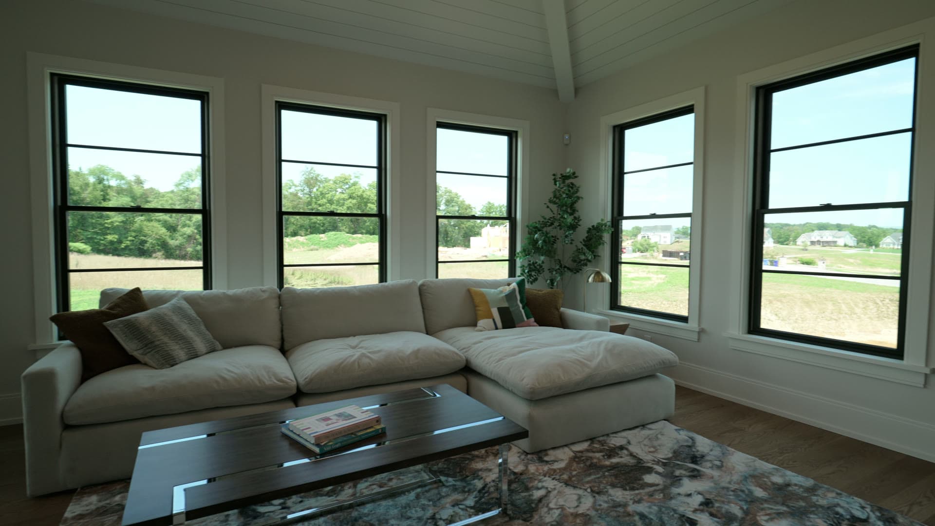 A living room with a sectional sofa under a wall of tall windows