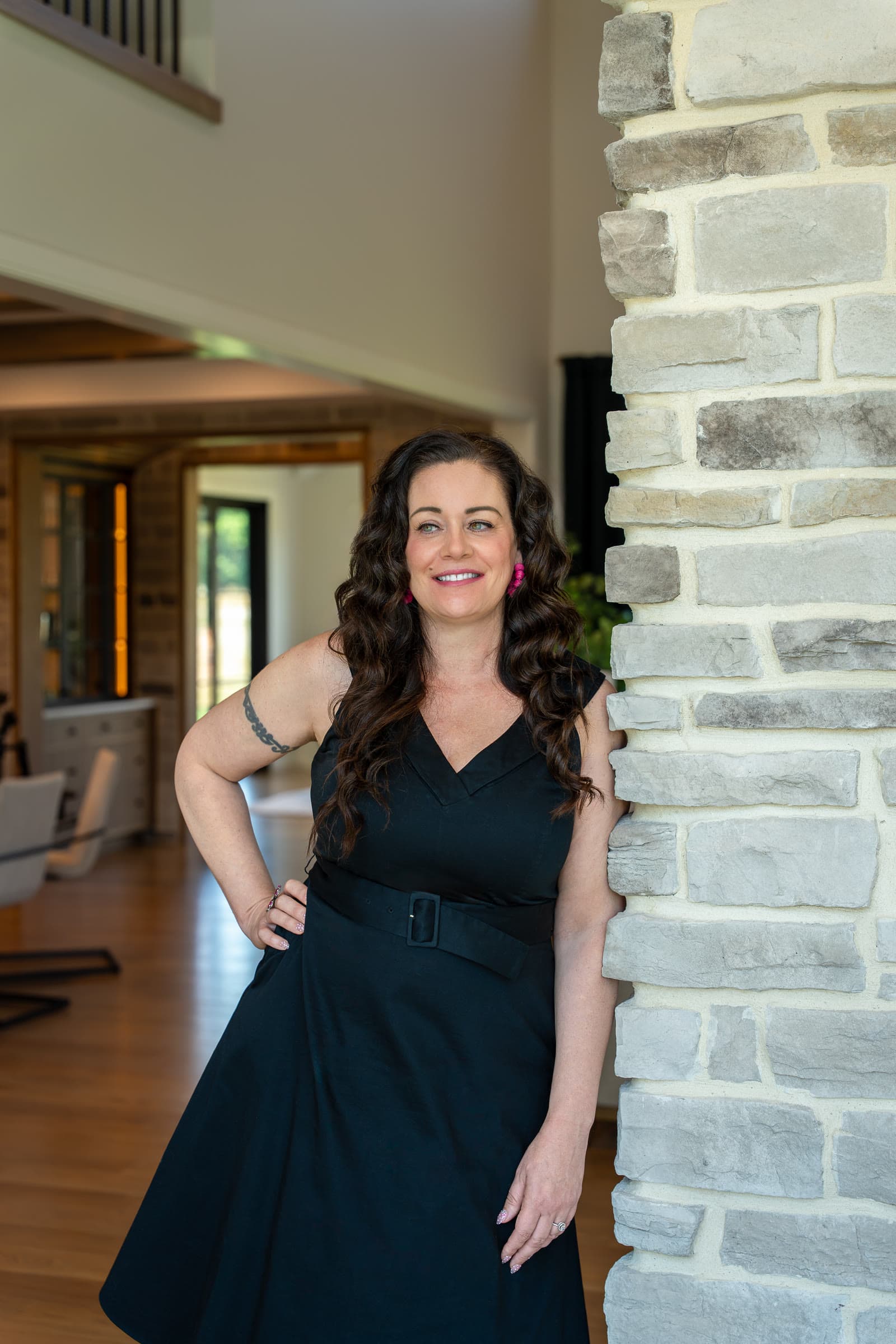 Shannon Clayton leaning against a stone column in a two storey entry