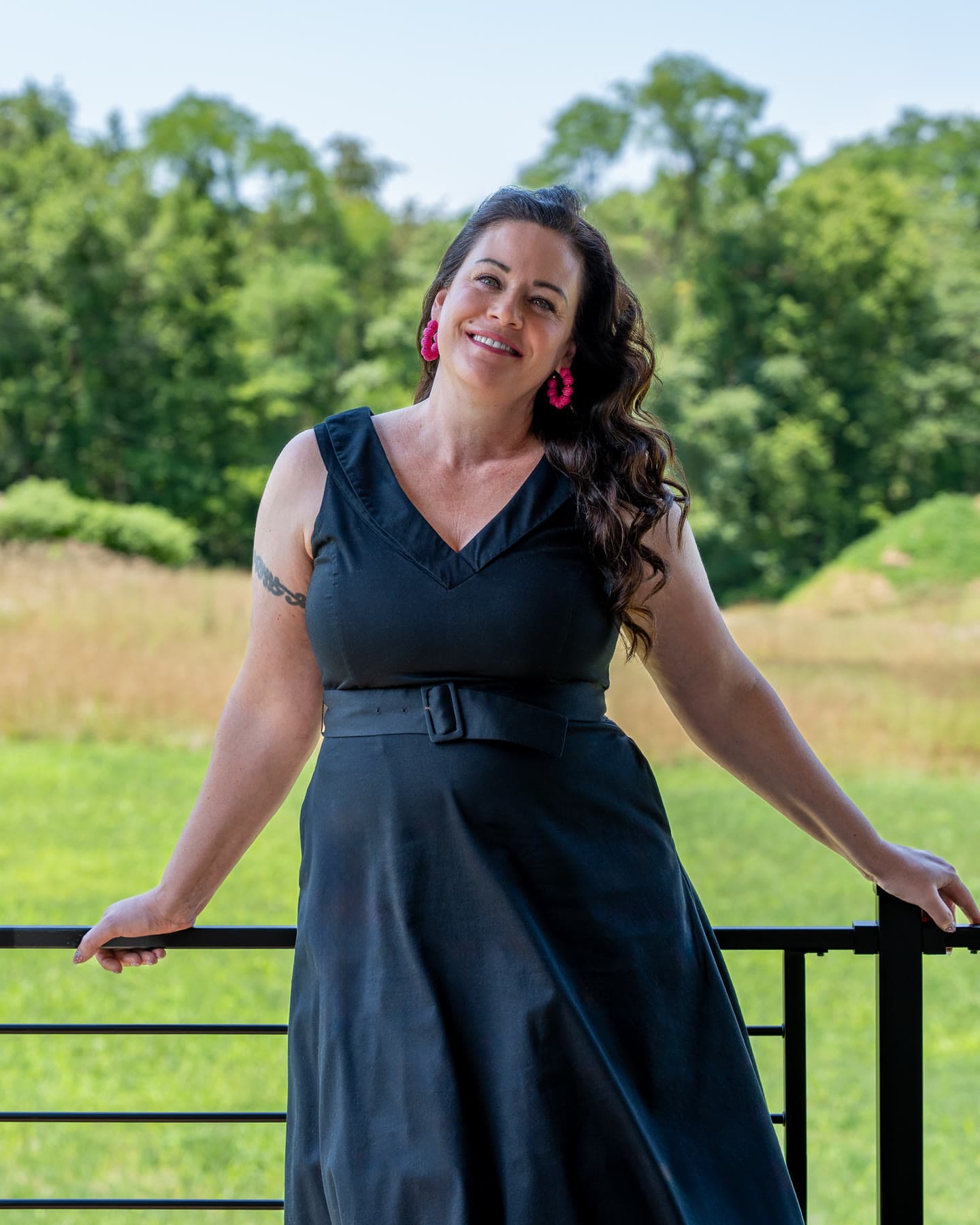 Shannon Clayton leaning on a porch railing with a meadow and woods behind her