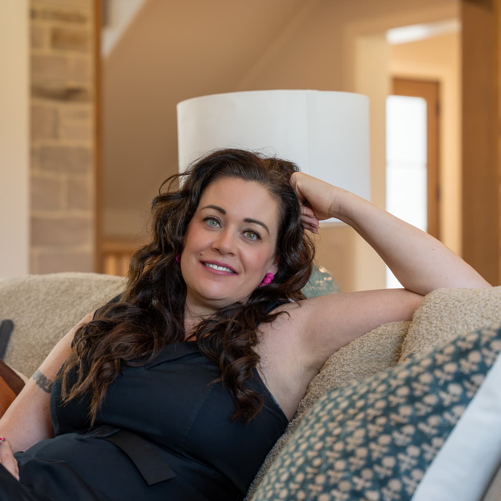 Shannon Clayton relaxing on a sofa, smiling at the camera